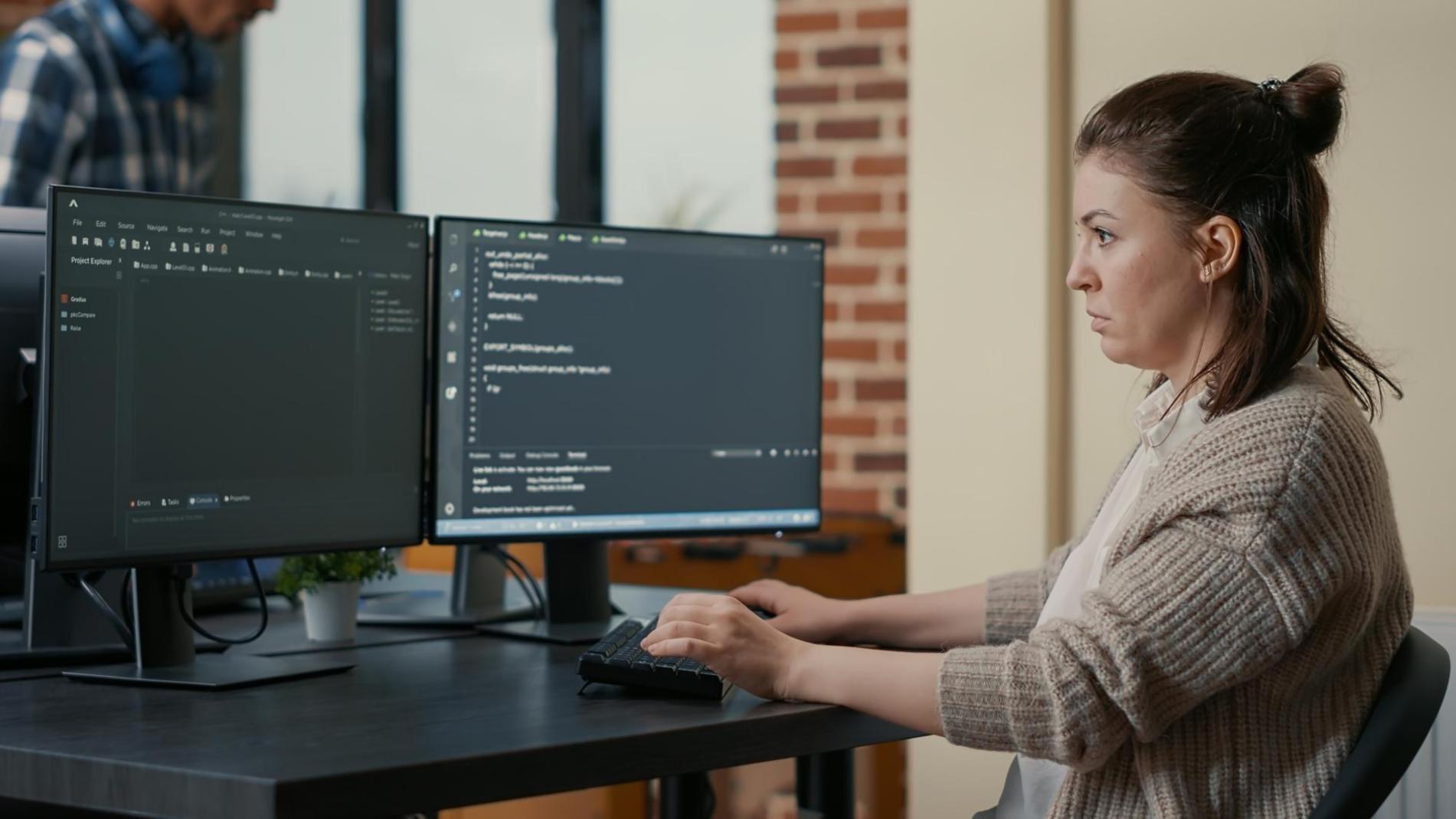 Student reviewing 3D level layout on dual monitors during evening class session